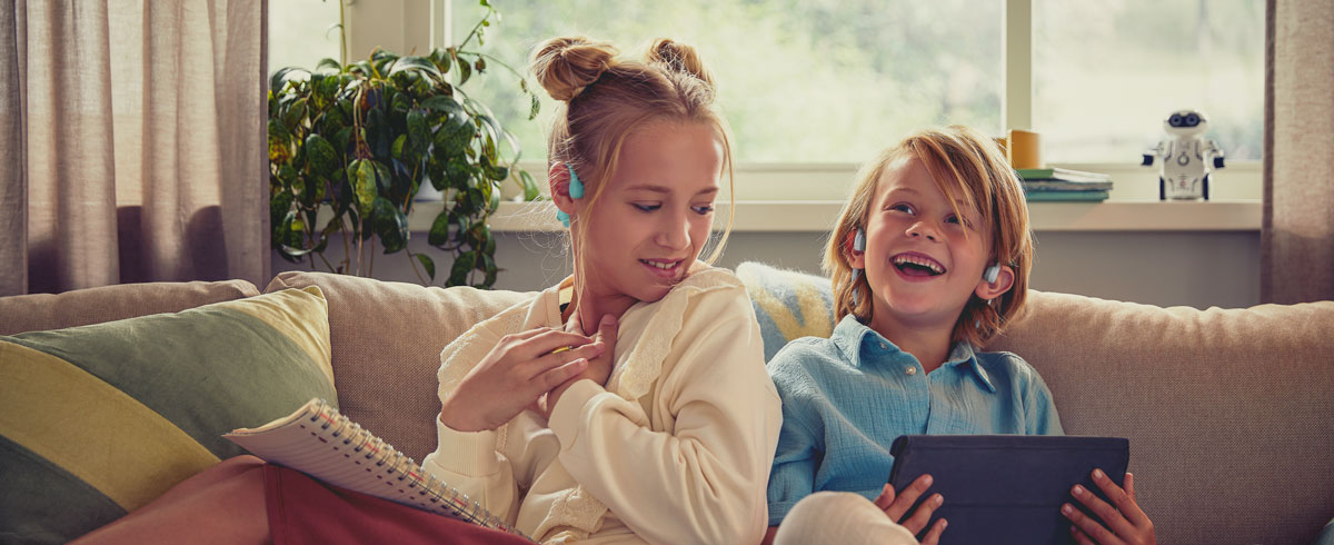 Παιδιά που απολαμβάνουν ένα βίντεο χρησιμοποιώντας ακουστικά ανοιχτού τύπου της Philips για παιδιά