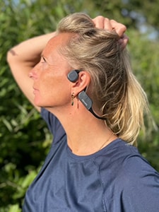 Γυναίκα που φοράει τα οστεοφωνικά ακουστικά Philips με Bluetooth