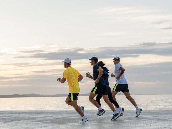 Τέσσερις συμμετέχοντες τρέχουν μαζί στην παραλία.